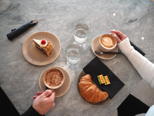 A person at a table with a cup of coffee and a plate of croissants, highlighting a relaxed morning atmosphere.