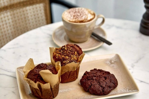 A plate with three muffins next to a cup of coffee, inviting a warm and comforting morning moment.