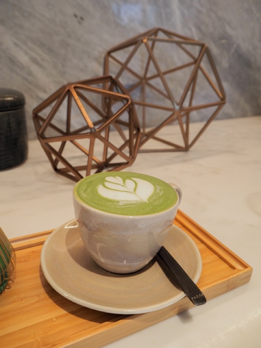 A cup of Matcha Latte placed on a wooden tray, showcasing a serene and inviting tea setting.